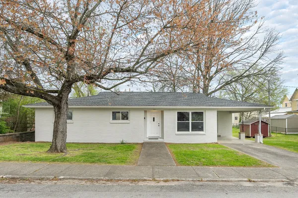 a front view of a house with a garden and trees