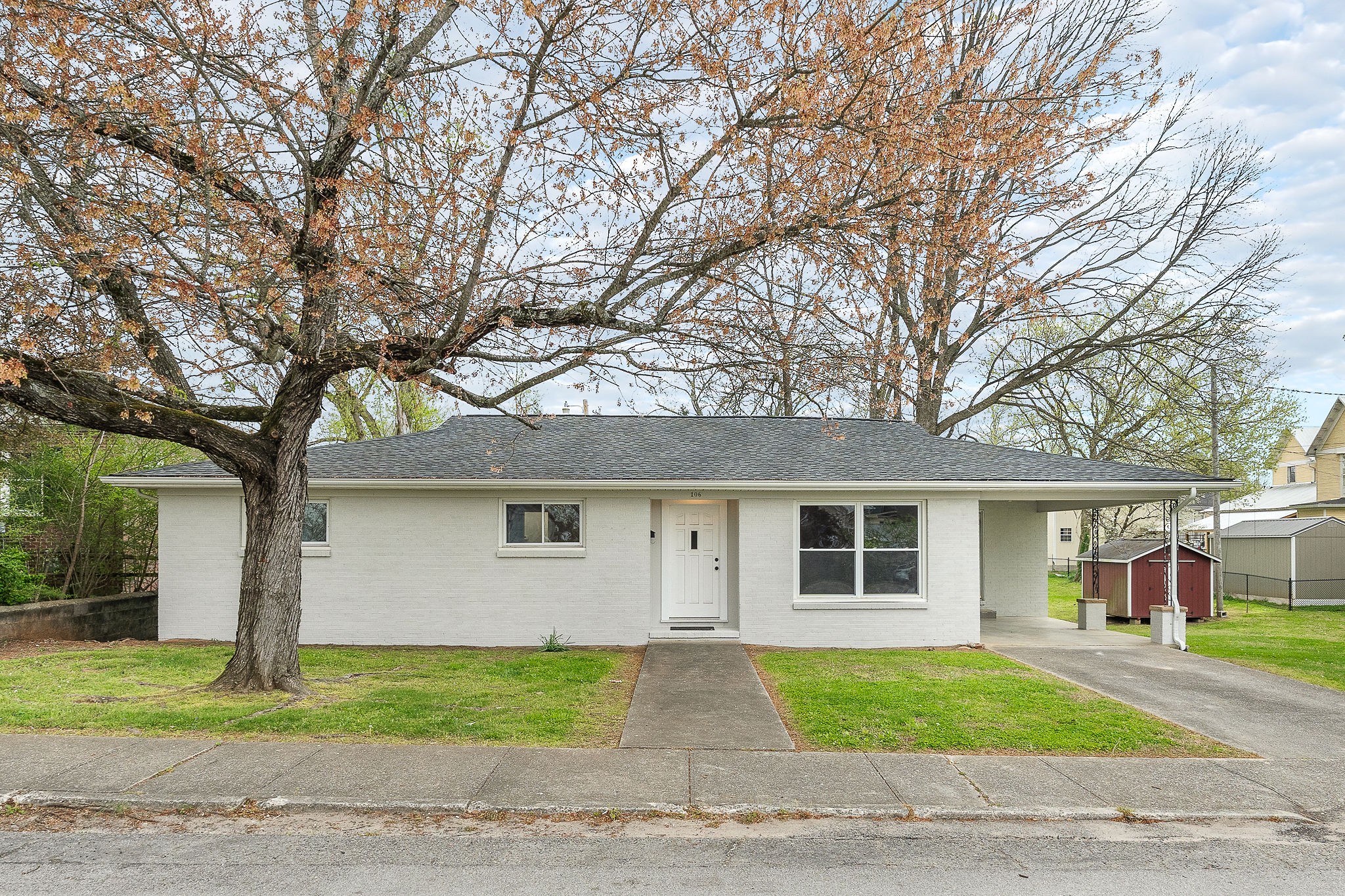 a front view of a house with a garden and trees