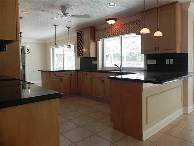 1 West High Point Road Sewall's Point, FL 34996 - Photo 3 of 20 a kitchen with kitchen island granite countertop a sink window and cabinets