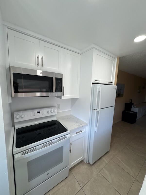 353 Highway 1, Unit A203 Jupiter, FL 33477 - Photo 15 of 26 a kitchen with white cabinets and stainless steel appliances