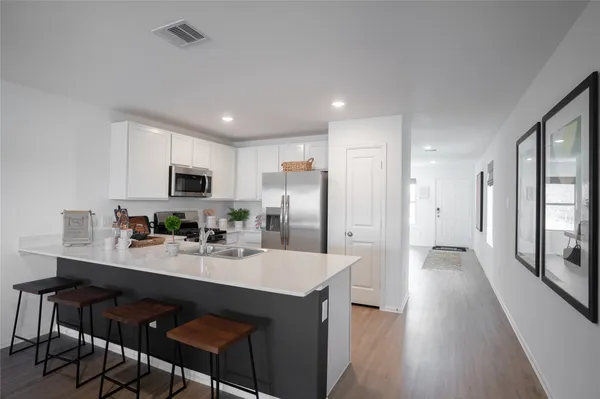 a kitchen with stainless steel appliances granite countertop a refrigerator a sink dishwasher and a stove with wooden floor