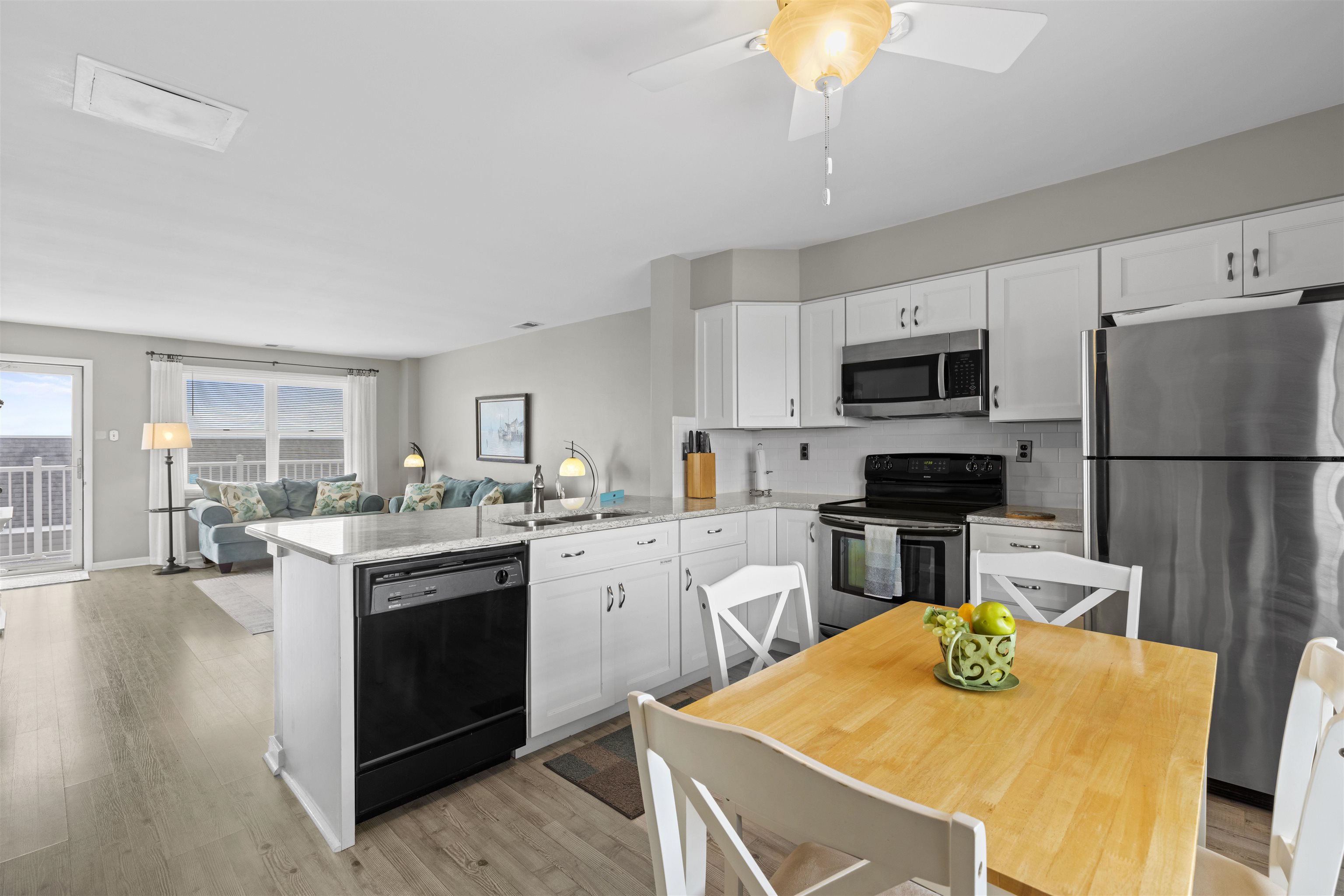 9 Jackson Street, Unit 506 Cape May, NJ 08204 - Photo 9 of 29 a kitchen with stainless steel appliances granite countertop a sink a stove a refrigerator a microwave oven with a dining table and chairs