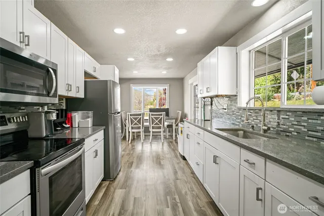 a kitchen with stainless steel appliances granite countertop sink stove top oven and cabinets