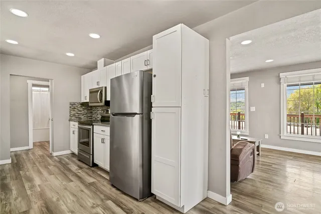 a kitchen with stainless steel appliances a refrigerator a stove a sink and a refrigerator with wooden floor