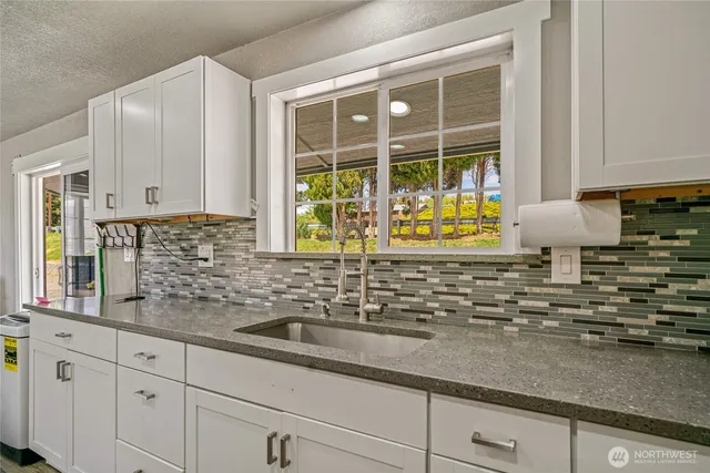 a kitchen with granite countertop a sink a stove and cabinets