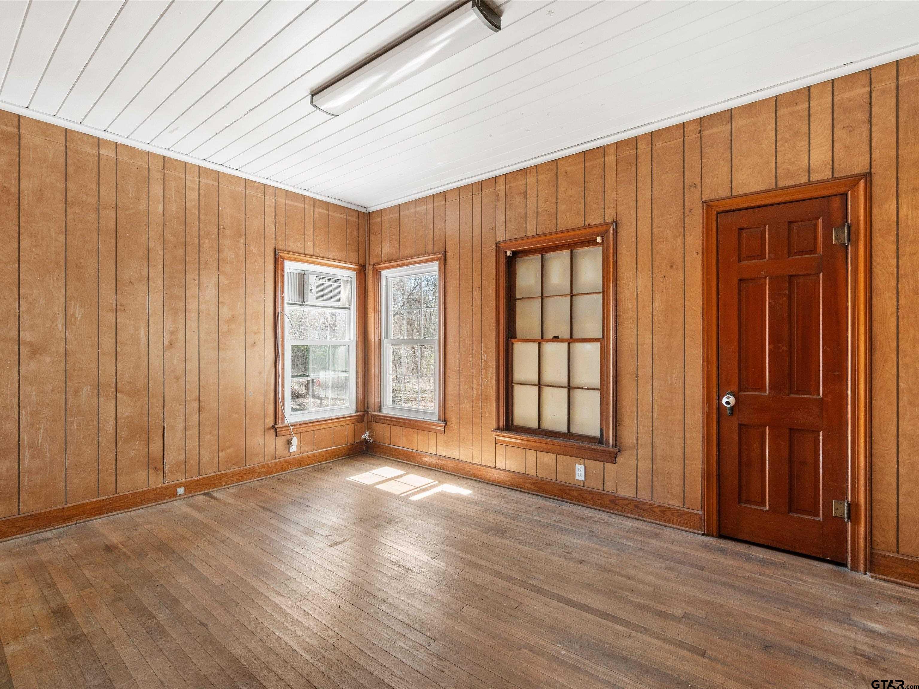 102 South Front Street Overton, TX 75684 - Photo 19 of 22 an empty room with wooden floor and windows with curtains
