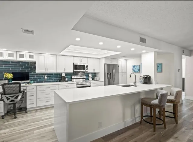 a large kitchen with kitchen island a sink a stove a dining table and chairs