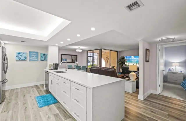 a large white kitchen with a stove a sink dishwasher and a refrigerator with wooden floor