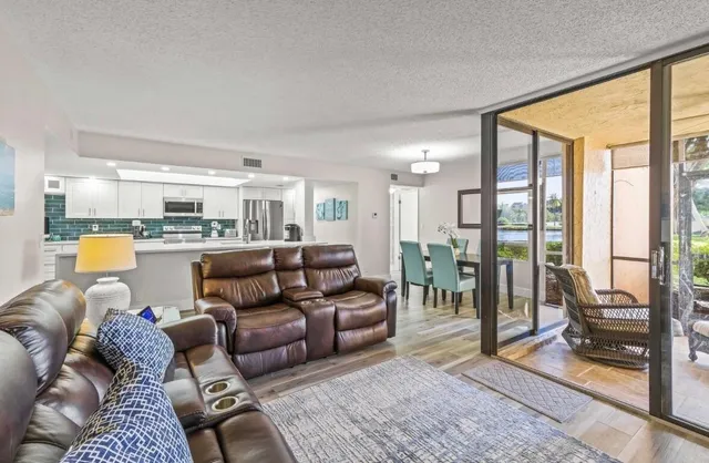 a living room with furniture floor to ceiling window and wooden floor