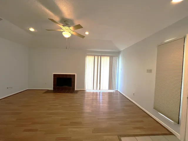 a view of an empty room with window and wooden floor