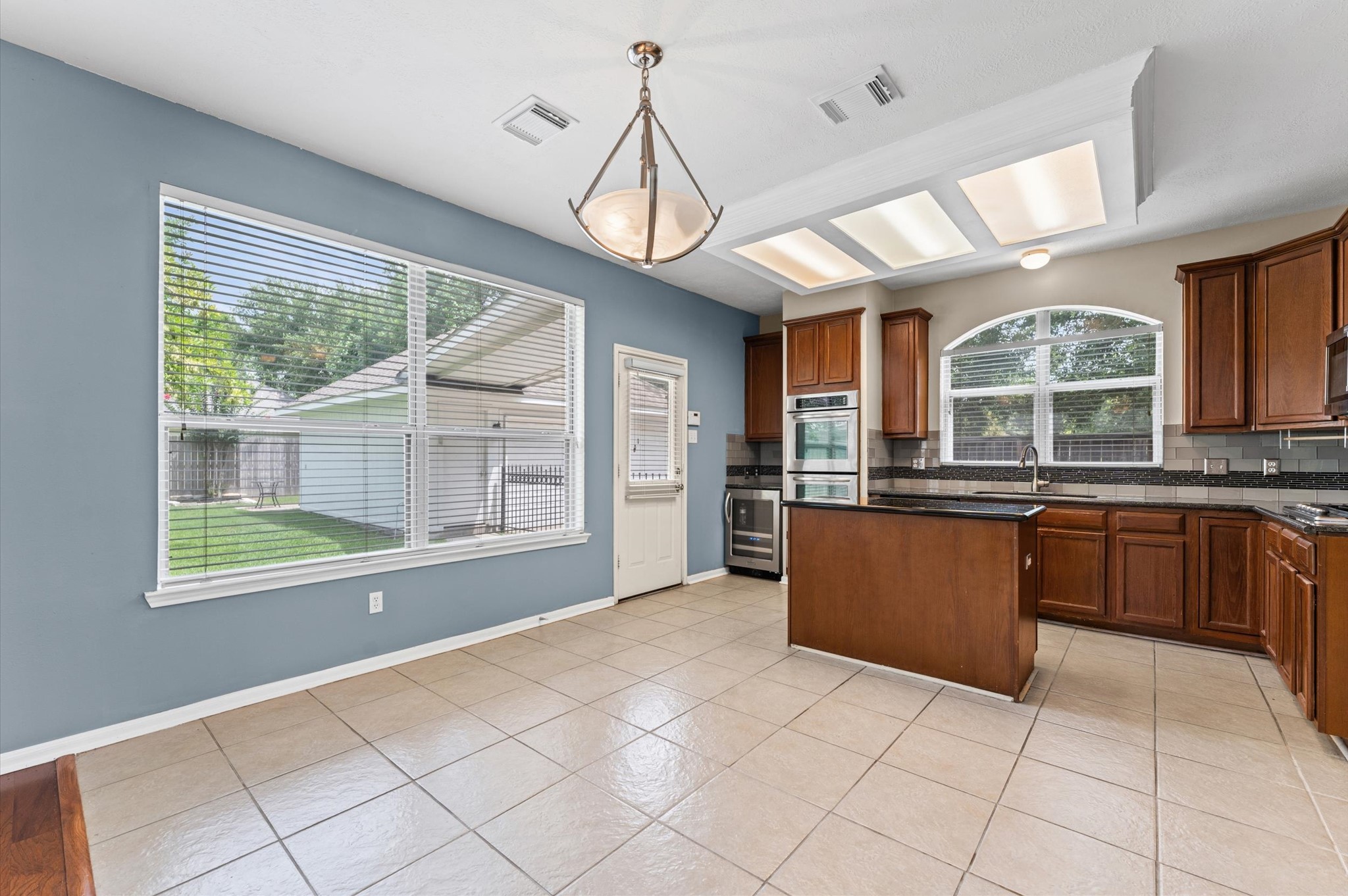 9202 State Walk Circle Houston, TX 77064 - Photo 8 of 25 This kitchen features ample natural light, tile flooring. It includes an island, Double- oven, and a large window overlooking a fenced yard. Perfect for family gatherings and cooking enthusiasts.