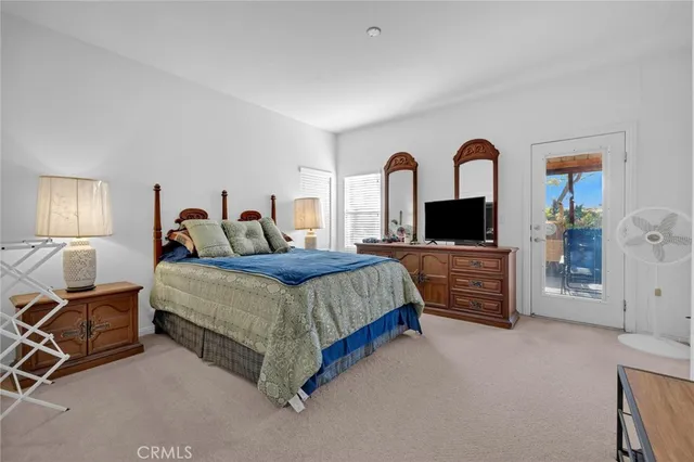 a spacious bedroom with a bed a table and a flat screen television