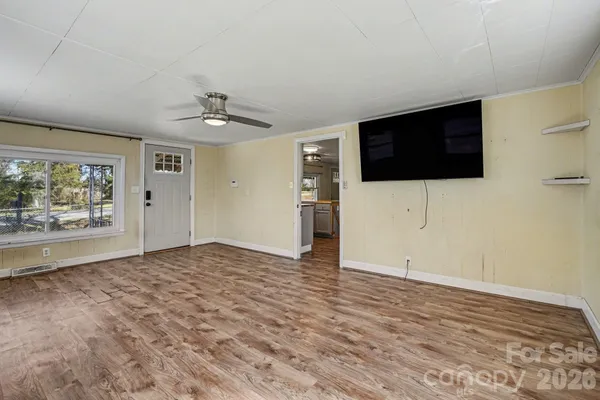 a view of an empty room with a window and a kitchen