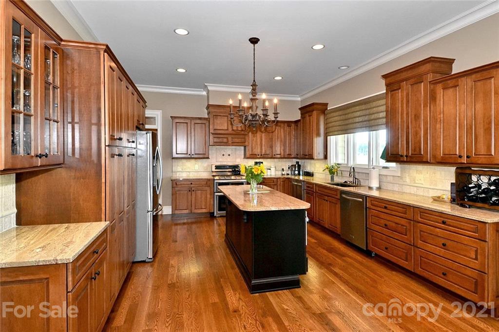 352 Windflower Ln Mill Spring Tryon, NC 28782 - Photo 6 of 43 a kitchen with stainless steel appliances granite countertop a refrigerator a sink dishwasher a stove and a dining table with wooden floor