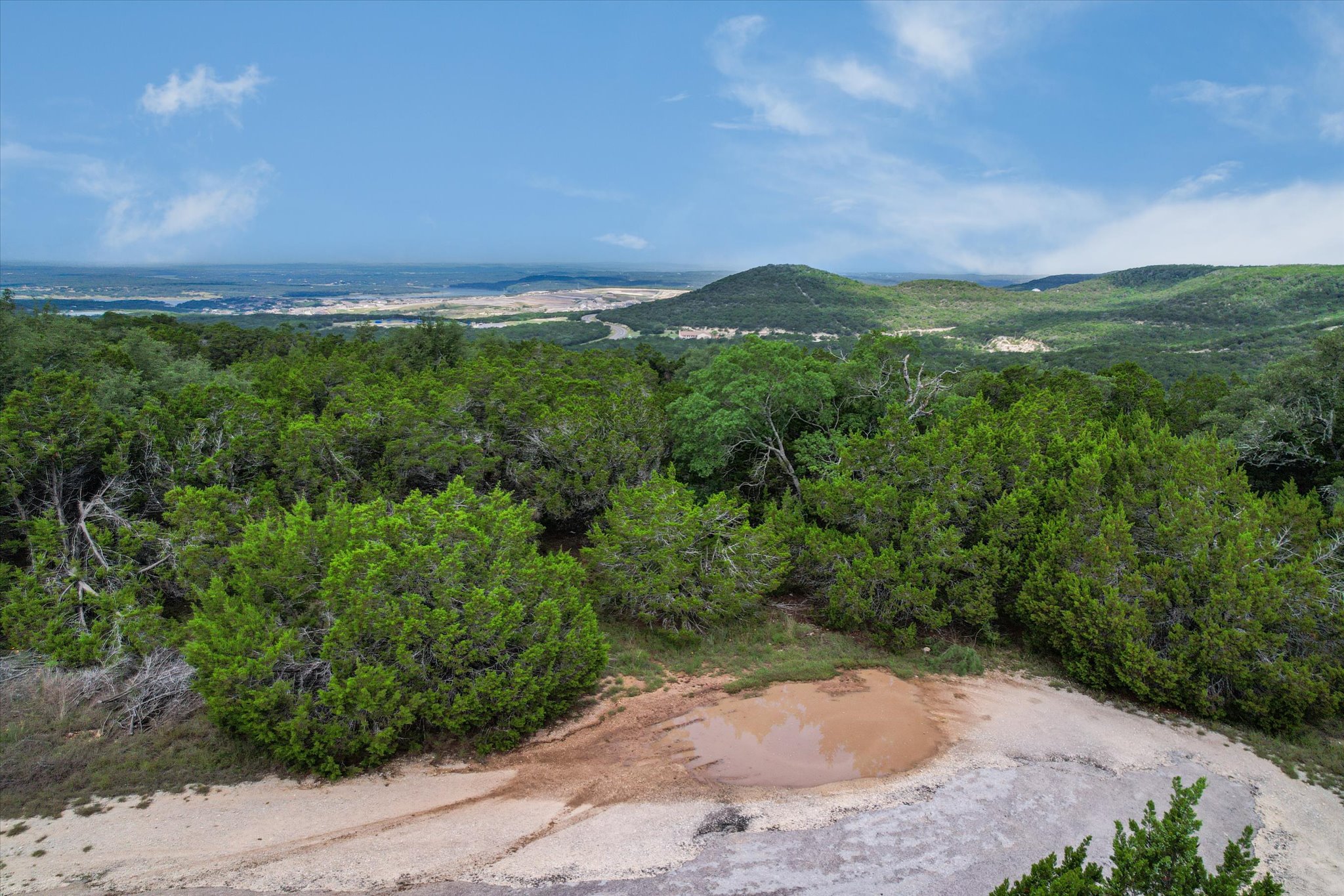 9404 Bar K Ranch Road Leander, TX 78645 - Photo 5 of 12 A tranquil, elevated vista reveals a verdant landscape with rolling hills and a distant town under an open sky.