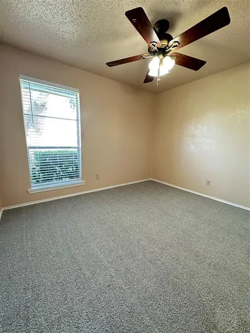 an empty room with chandelier fan and windows