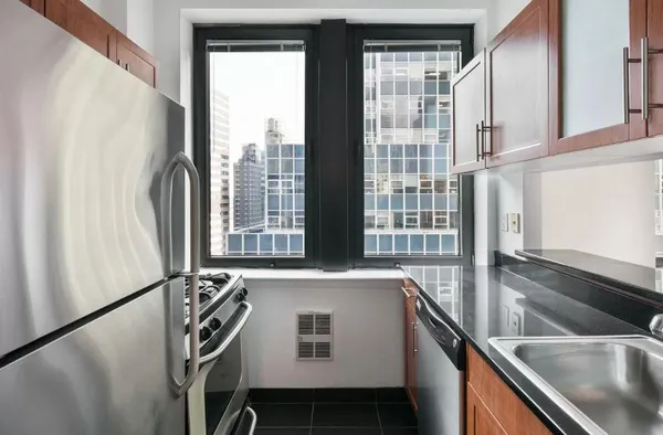 a kitchen with stainless steel appliances a sink a refrigerator and a window