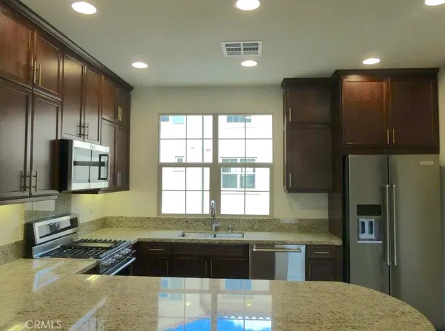 a kitchen with stainless steel appliances granite countertop a refrigerator and a sink