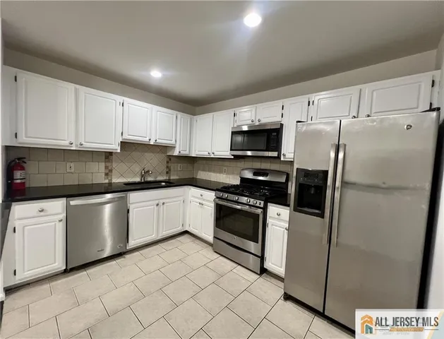 a kitchen with granite countertop cabinets stainless steel appliances and a counter space