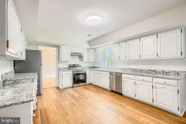a kitchen with granite countertop white cabinets and white appliances