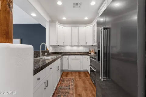 a kitchen with granite countertop white cabinets and stainless steel appliances