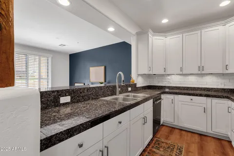 a kitchen with granite countertop a sink and a white wooden cabinets