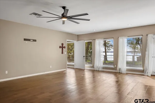 a view of an empty room with a window and wooden floor