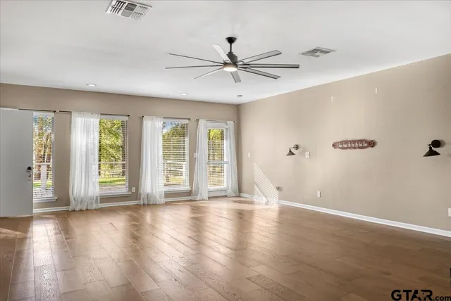 a view of an empty room with a window and wooden floor