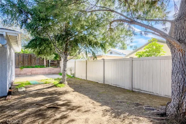 a view of a yard with wooden fence and a tree