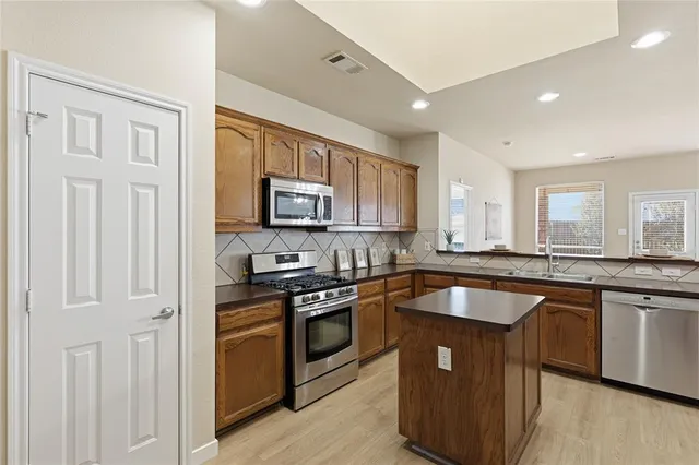 a kitchen with stainless steel appliances granite countertop a stove a sink and a microwave