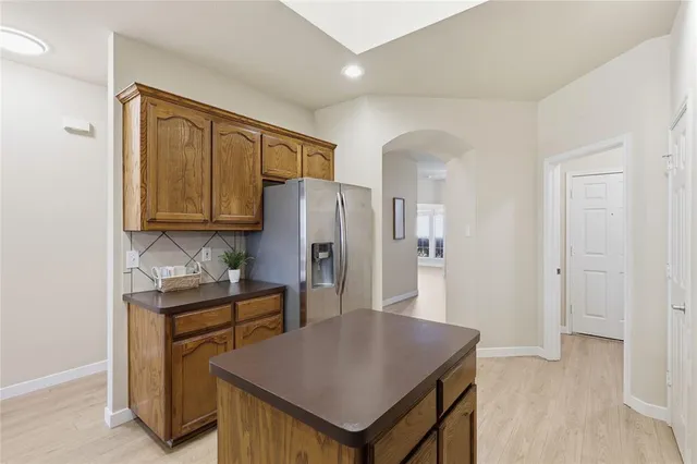 a kitchen with stainless steel appliances granite countertop a refrigerator a stove a sink and a white cabinets