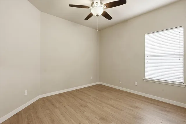 an empty room with a window and a fan