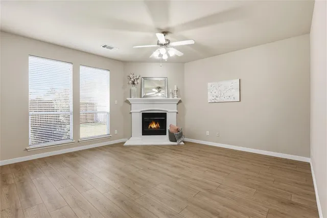 a view of an empty room with wooden floor fireplace and a window