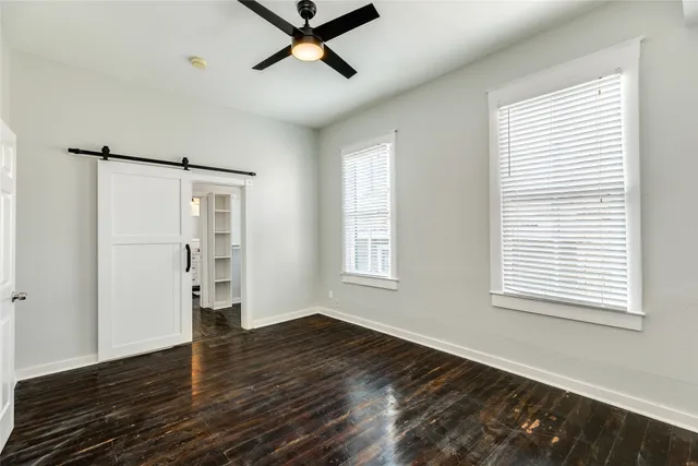 a view of empty room with wooden floor and fan