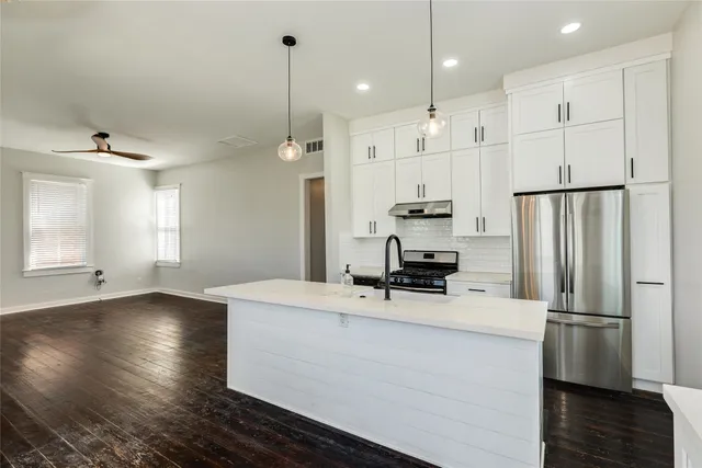 a kitchen with stainless steel appliances a refrigerator sink and wooden floor