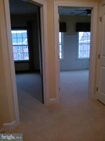 an empty room with windows and chandelier fan