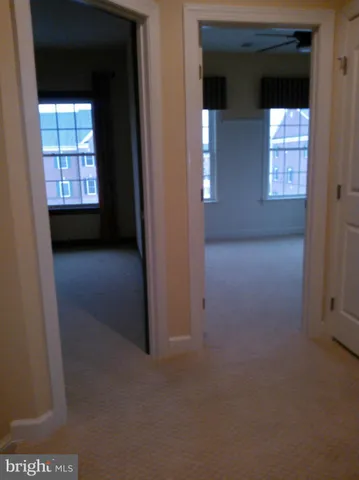 an empty room with windows and chandelier fan
