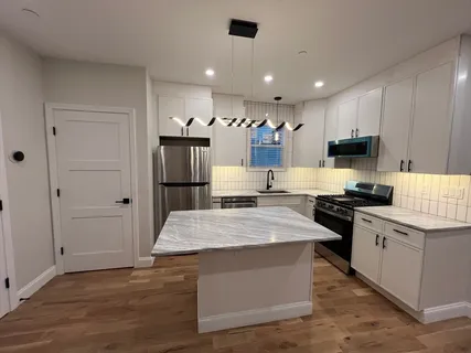 a large kitchen with stainless steel appliances kitchen island granite countertop a stove and a refrigerator