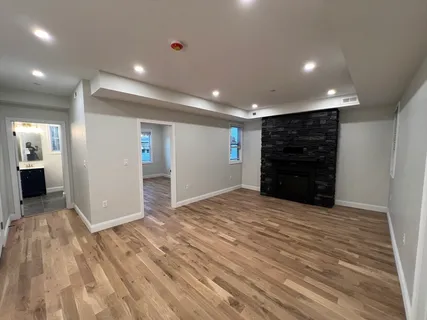 a view of an empty room with wooden floor and closet