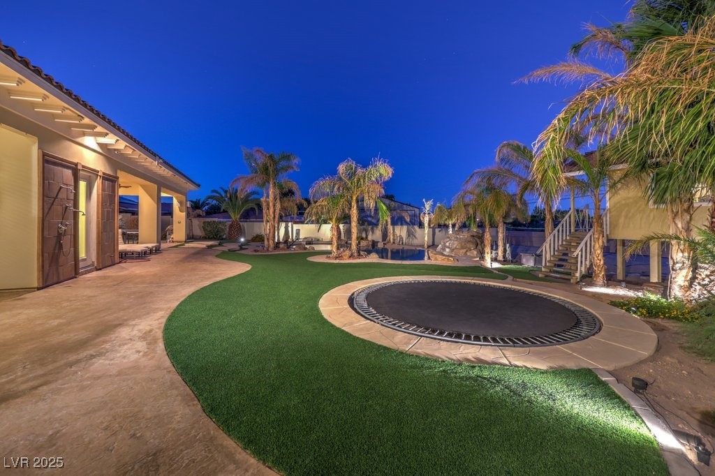 2780 El Camino Road Las Vegas, NV 89146 - Photo 15 of 91 Yard at night featuring a patio, a yard, and a trampoline