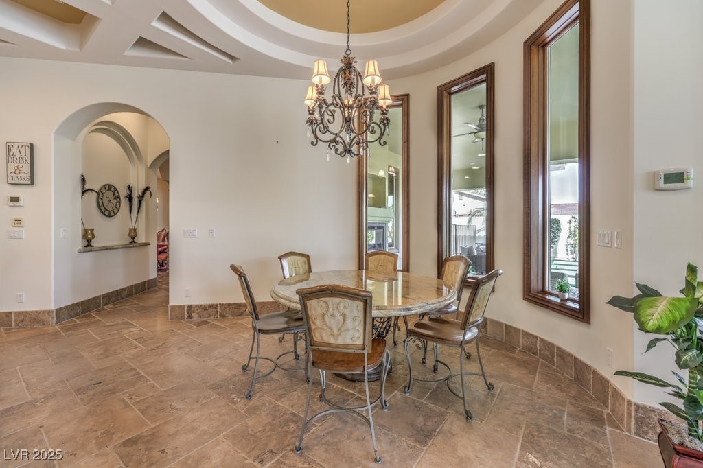 2780 El Camino Road Las Vegas, NV 89146 - Photo 33 of 91 Dining room with arched walkways, a chandelier, a raised ceiling, and stone tile flooring