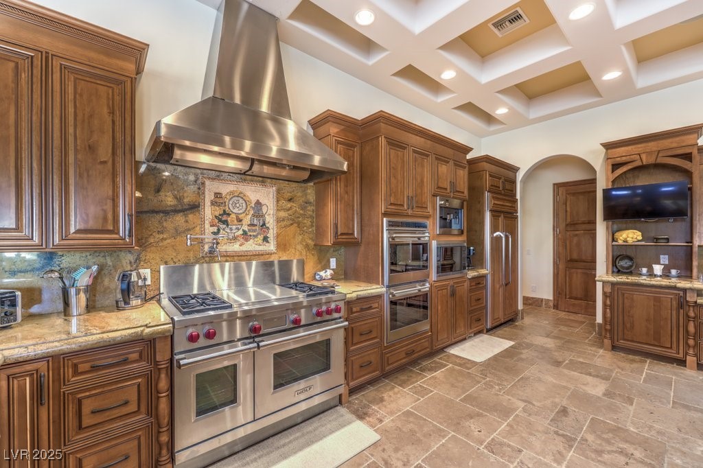 2780 El Camino Road Las Vegas, NV 89146 - Photo 38 of 91 Kitchen featuring high end appliances, exhaust hood, coffered ceiling, light stone counters, and tasteful backsplash