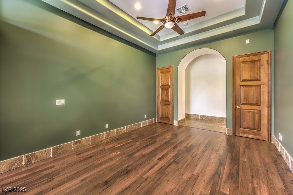 2780 El Camino Road Las Vegas, NV 89146 - Photo 60 of 91 Empty room with a tray ceiling, dark wood-style floors, arched walkways, and ceiling fan