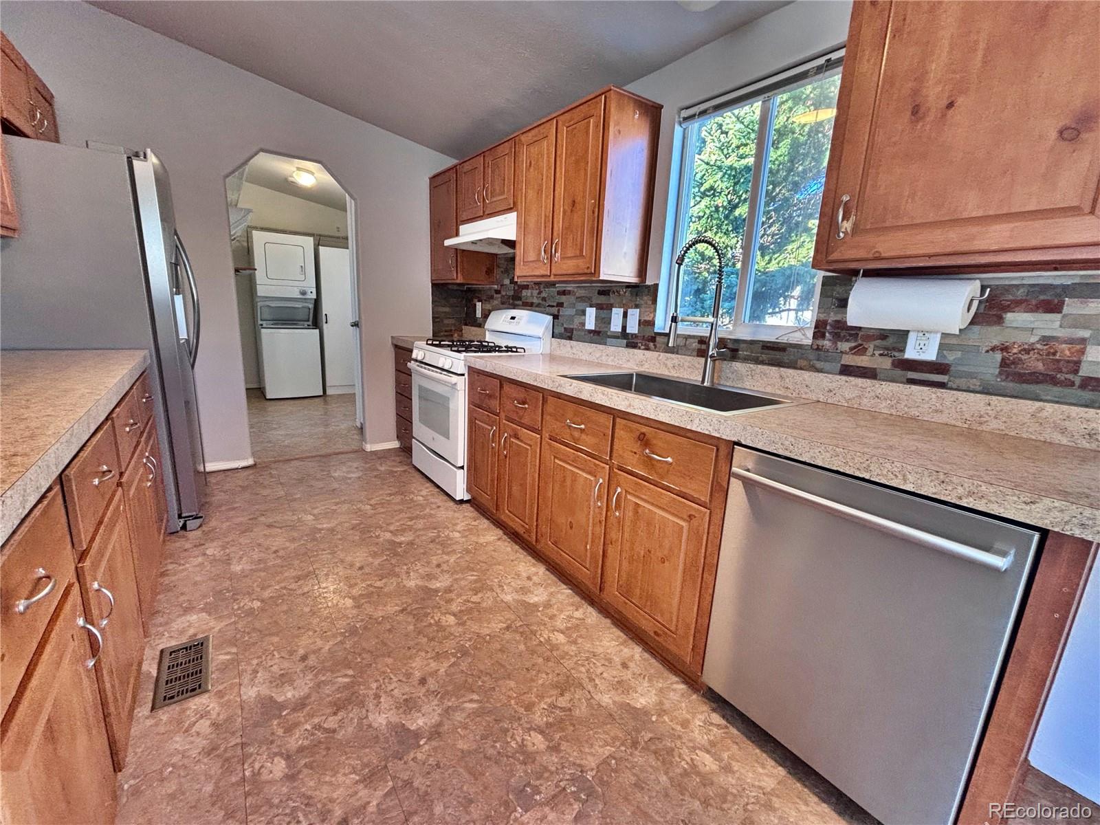 155 A Street Golden, CO 80401 - Photo 18 of 49 a kitchen with stainless steel appliances granite countertop a refrigerator a sink dishwasher a stove a washer and dryer with wooden cabinets