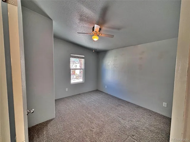an empty room with closet and fan