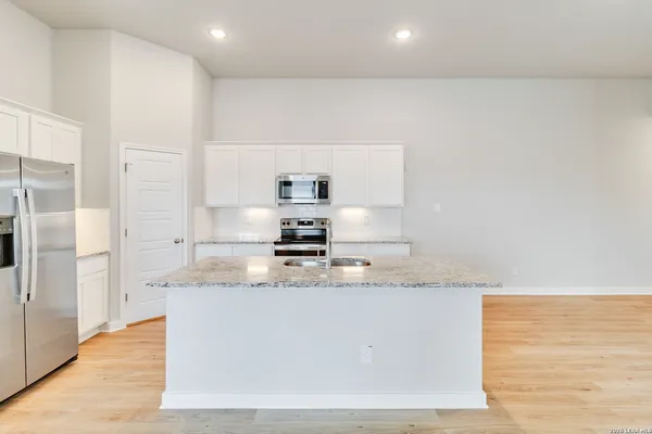 a large kitchen with granite countertop a sink a center island stainless steel appliances and cabinets