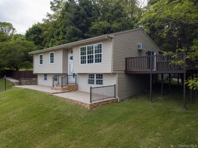 a view of a white house next to a yard with large trees