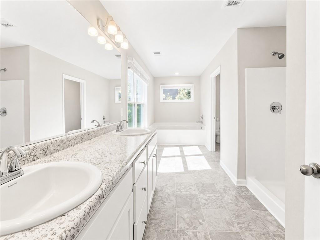 524 Rippling Court Temple, GA 30179 - Photo 15 of 19 a spacious bathroom with a granite countertop sink a mirror and a bathtub
