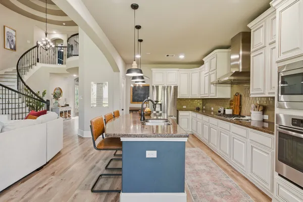 a large white kitchen with stainless steel appliances kitchen island granite countertop a refrigerator a stove top oven a sink and dishwasher