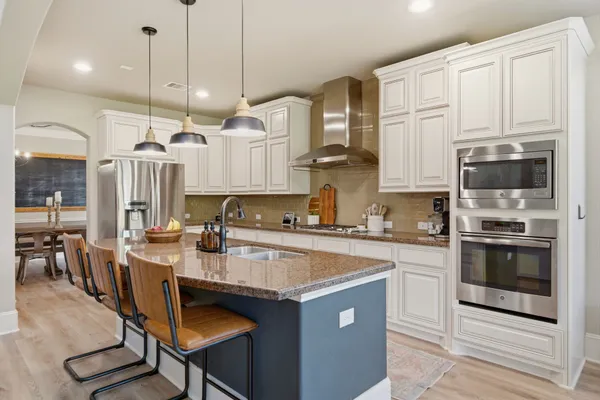 a kitchen with kitchen island granite countertop a stove a sink a center island and cabinets